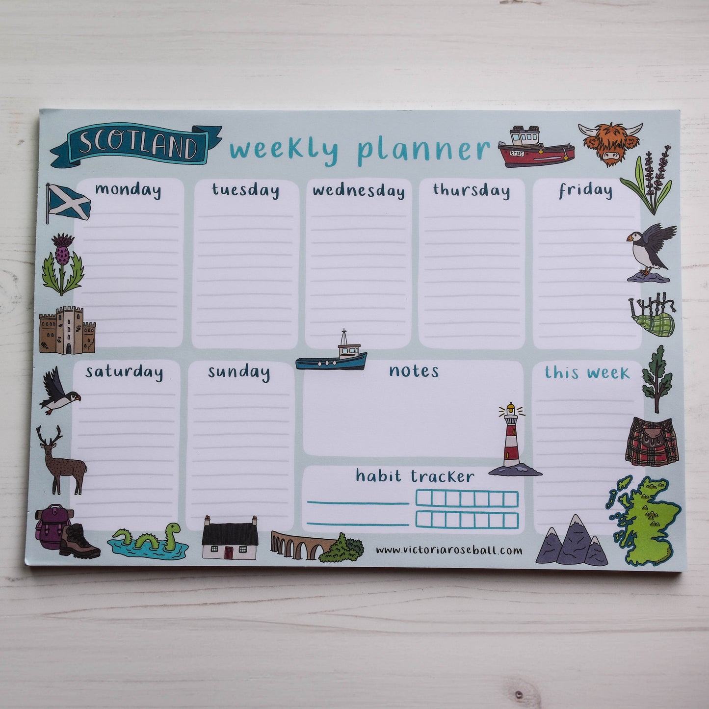 Weekly planner with Scottish-themed icons on a light wooden surface