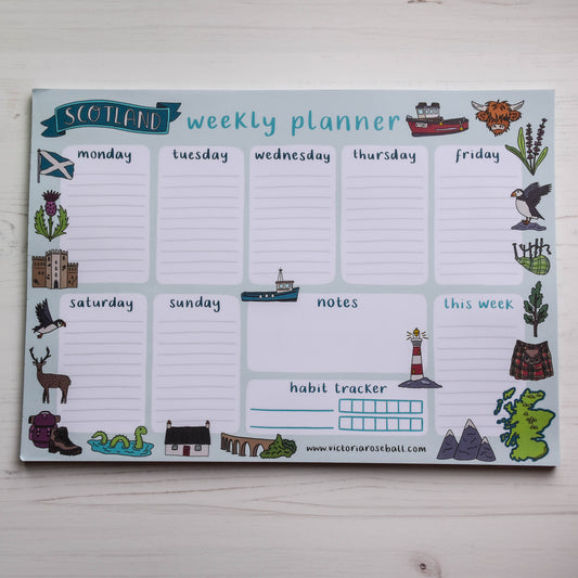 Weekly planner with Scottish-themed icons on a light wooden surface