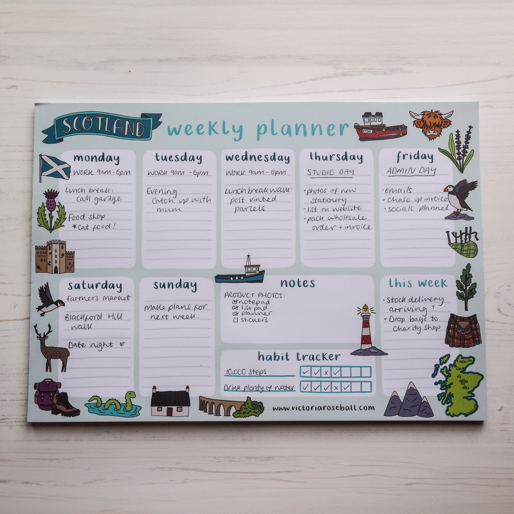 Weekly planner with Scottish-themed illustrations on a wooden surface