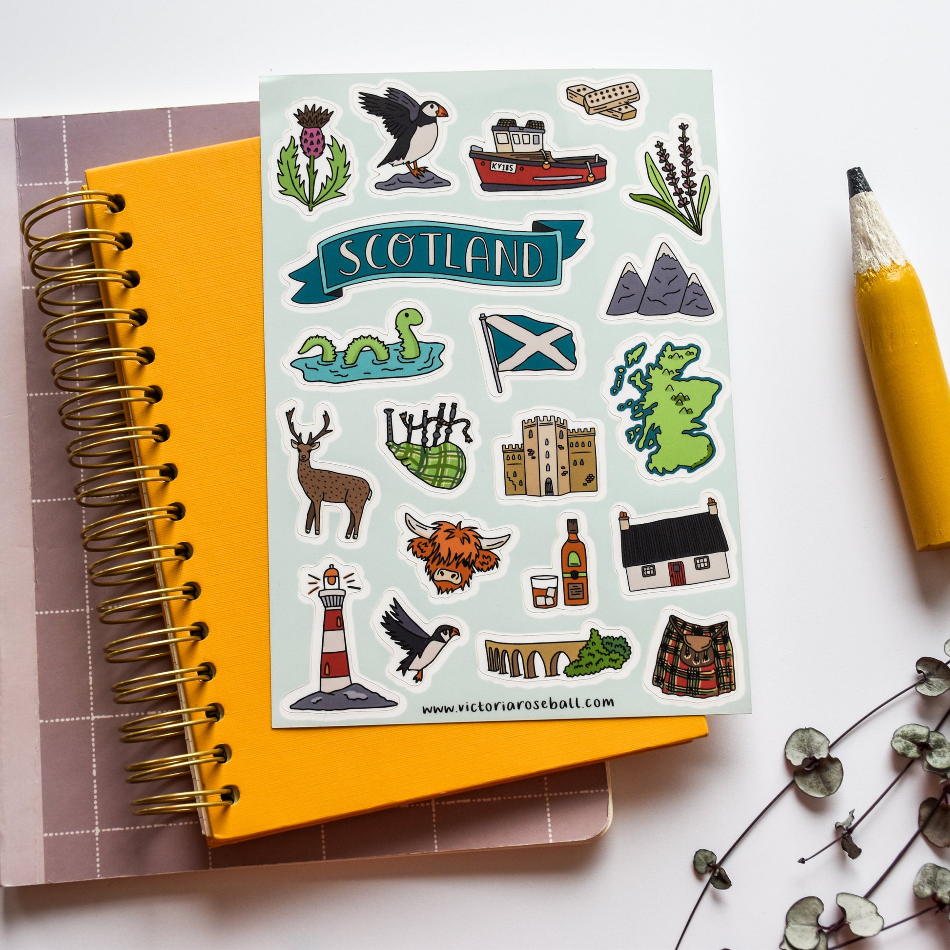 Notebook with Scottish-themed stickers and a yellow pen on a white background