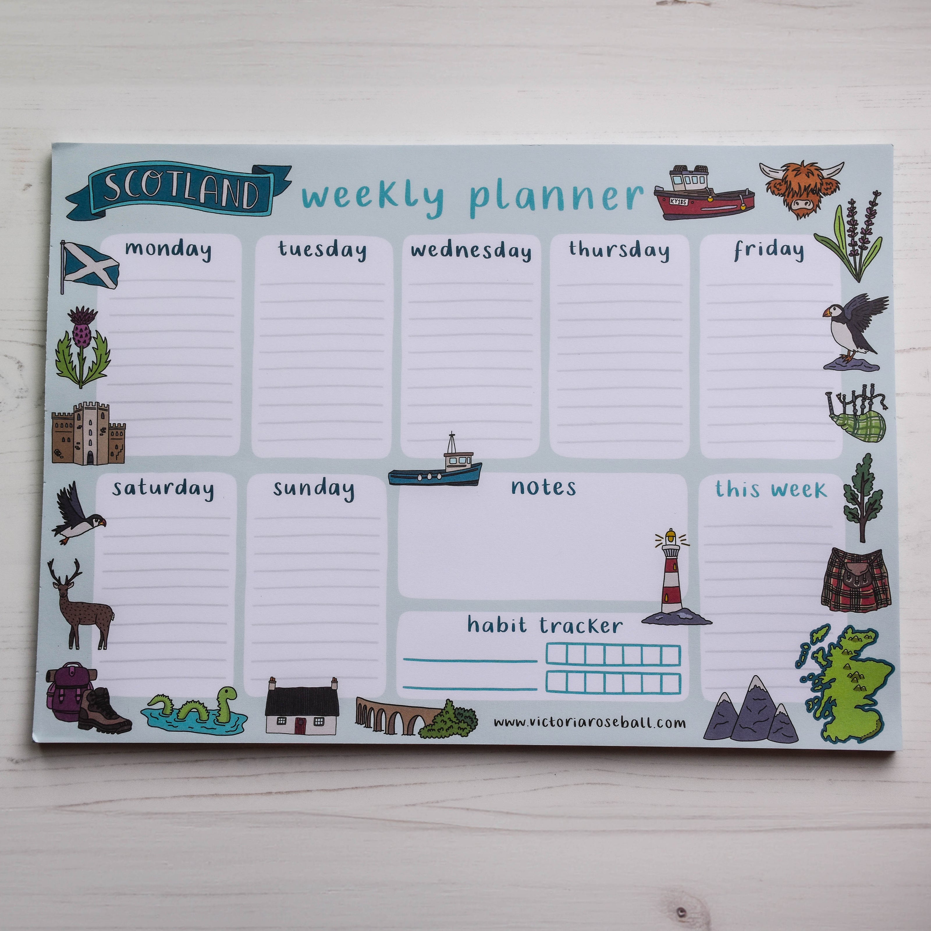 Weekly planner with Scottish-themed icons on a light wooden surface