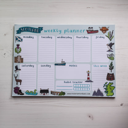 Weekly planner with Scottish-themed icons on a light wooden surface