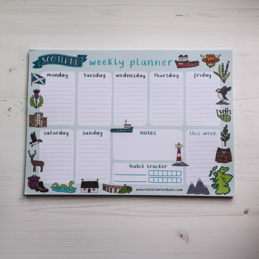 Weekly planner with Scottish-themed icons on a light wooden surface